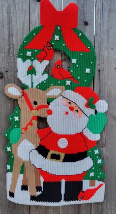 a christmas ornament hanging on the side of a wooden fence with santa claus and deer