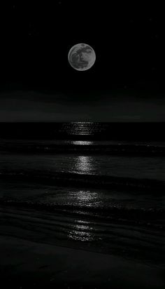 the full moon shines brightly over the ocean at night with black and white colors