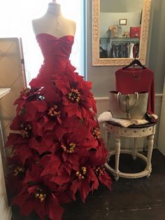 a dress made out of poinsettia is on display in a room with a mirror