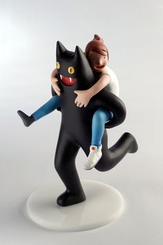 a figurine is holding a black cat on its back while it's being hugged