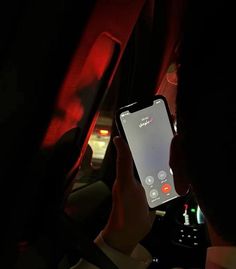 a person is using their cell phone while driving in the dark with red lights on