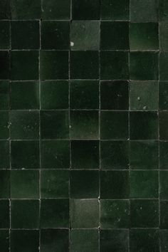 a black and green tiled wall with some white dots on the bottom right hand corner