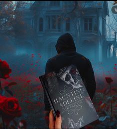 a person holding a book in front of a house with red roses on the ground