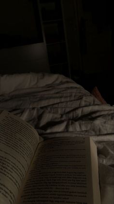 an open book sitting on top of a bed