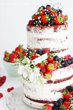 a three layer cake with berries and flowers on top