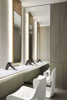 a row of white chairs sitting next to each other in front of a bathroom mirror