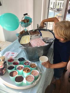 a little boy standing in front of a table filled with desserts and ice cream