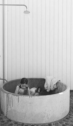 black and white photograph of two people in a bathtub