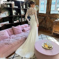 a woman in a white wedding dress standing next to a pink couch and coffee table