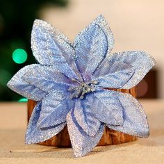 a small blue flower sitting on top of a wooden table next to a christmas tree