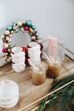 there are two cups with drinks on the table next to each other and a wreath in the background