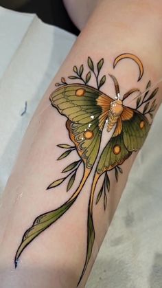 a small butterfly tattoo on the arm with flowers and leaves around it's wings