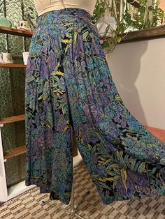 Fantastic pair of 80s era high rise wide leg rayon cropped pants or culottes/gaucho pants. Lovely tapestry or needlepoint style floral print in a vibrant mix of colors, including purple, turquoise, green, and chartreuse on a black background. Elasticized at the back of waistband, front of waistband does not have stretch. There is a button closure on the left side of these pants. The closure sort of forms a pocket, but it's not very deep. There is also a pocket on the right side. 100% rayon. These pants are great! Size medium to large.  Measurements are below, taken while lying flat and then doubled where appropriate. Waist: 18" unstretched, can stretch to about 32" or so Rise: 15.5" Inseam: 19.5" Outseam: 34" These fall to about mid-shin on my 5' 5.5" frame. I'm about a size 6, and they fi Multicolor Ankle-length Wide Leg Pants With Pockets, Vintage Multicolor Wide Leg Pants, Retro Multicolor Wide-leg Bottoms, Multicolor Floral Print High-waisted Wide Leg Pants, Festival Floral Print Wide-leg Pants, 80s Era, 80s Floral, Gaucho Pants, Wide Leg Crop Pants