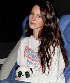 a woman sitting in a chair holding a stuffed panda bear