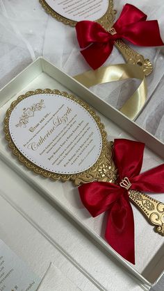 two wedding cards in a box with red ribbon and bows on the front, one is gold