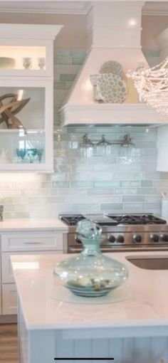 a kitchen with white cabinets and a glass bowl on the center island in front of an oven