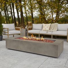 a fire pit sitting on top of a patio next to two couches and trees