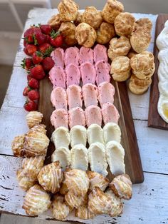 there are many different types of pastries on this wooden platter with strawberries