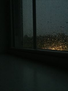 the rain is coming down on the window and it's raining in the dark