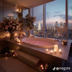 a bathtub with candles and flowers in front of a large window overlooking the city