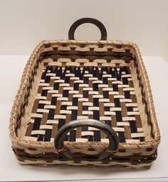 a woven basket sitting on top of a white table next to a black ring handle