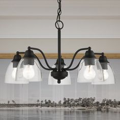 three light chandelier with clear glass shades hanging from the ceiling over a body of water