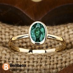 a close up of a ring with a green stone in it on a wooden surface