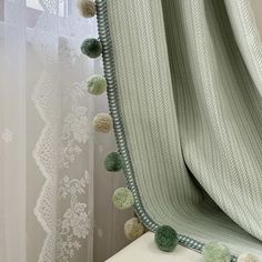 a curtain with pom - poms hanging from it's side in front of a window