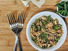 a white plate topped with rice and vegetables next to a bowl of green beans on top of a wooden table