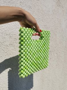 a hand holding a green bag made out of balls