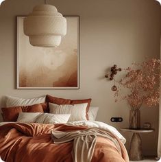 a bed with an orange comforter in a bedroom next to a painting on the wall