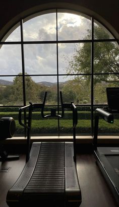 an exercise room with treadmills in front of a large window that looks out onto the countryside