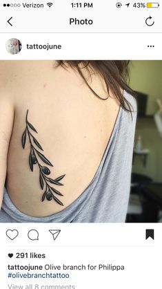 the back of a woman's shoulder with an olive branch tattoo on it