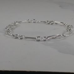 Every link in this silver chain is soldered for strength, with a hand-made silver hook and eye fastening to keep it securely on your wrist. The design features figure-of-eight shapes linked by ovals of round section sterling silver wire. You can adjust the length to suit your wrist by linking the hook into different eyes. Sterling Silver Link Paperclip Bracelet, Sterling Silver Paperclip Link Bracelet, Sterling Silver Oval Link Chain Bracelet With Clasp, Sterling Silver Oval Link Chain Bracelet, Silver Sterling Silver Link Paperclip Bracelet, Sterling Silver Link Bracelets With Paperclip Chain, Sterling Silver Bracelets With Paperclip Chain, Sterling Silver Paperclip Bracelet With Oval Links, Sterling Silver Link Chain Bracelet