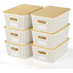 four white storage baskets stacked on top of each other with wooden lids and handles in the shape of rectangles