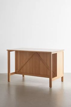 a wooden table sitting on top of a hard wood floor next to a white wall