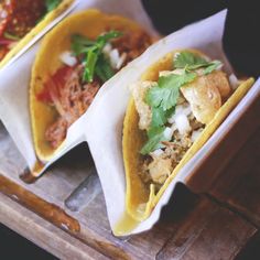 three tacos sitting on top of a wooden tray