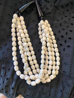 This ivory statement necklace has multiple strands of beads with a horn clasp hook. Elegant Beaded Necklace With Wooden Beads, White Multi-strand Beaded Necklace With Wooden Beads, Cheap Statement Multi-strand Beaded Necklaces, Elegant Multi-strand Necklaces With Wooden Beads, White Multi-strand Necklace With Wooden Beads, White Multi-strand Necklace With Large Beads, Elegant Multi-strand Necklace With Wooden Beads, Cheap Multi-strand Statement Beaded Necklaces, White Multi-strand Wooden Beaded Necklaces