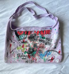 a handbag that has been covered in graffiti and is laying on a white sheet