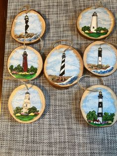 six hand painted plates with lighthouses on them are sitting on a tablecloth covered surface