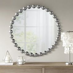 a mirror on the wall above a dresser with candles and vases in front of it