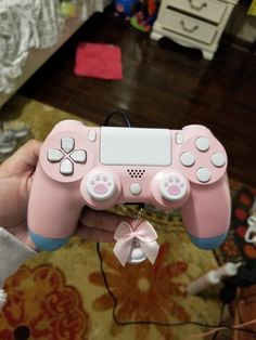 a person holding a pink video game controller in their hand with a bow on it