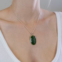 The darker greens in this Nephrite Jade necklace give you more freedom to express yourself. It's a simple neutral gemstone necklace that will brighten your day when paired with other gems. It's all about harmonizing energy with this old, precious crystal necklace. Stone Origin: New Zealand Measures Approximately: 35 x 22 mm Materials: Hand Crafted 925 Polished Sterling Silver and adjustable Italian Belcher chain Please Note: If you would like to purchase a different chain please purchase pendant Jade Oval Pendant Necklace With Natural Stones, Jade Necklace With Oval Pendant And Natural Stones, Green Gemstone Crystal Necklace With Round Pendant, Green Necklace With Oval Pendant And Natural Stones, Green Oval Pendant Necklace With Natural Stones, Green Oval Pendant Necklace For Spiritual Style, Green Oval Pendant Necklace Spiritual Style, Spiritual Green Oval Pendant Necklace, Green Oval Necklace With Large Stone