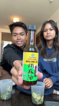 a man and woman sitting at a table holding up a bottle of ketchup