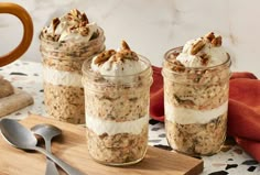 three jars filled with food sitting on top of a wooden cutting board next to spoons