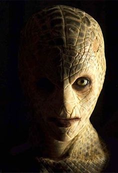 a close up of a person wearing an alien costume with eyes wide open in the dark