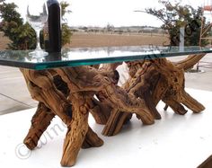 a table made out of driftwood with a glass top and wine bottle on it