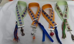 four different colored lanyards with charms attached to them on a white cloth covered surface