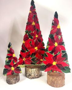 three red poinsettia trees sitting on top of wooden stumps next to each other