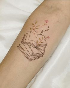 a tattoo on the arm of a woman with an open book